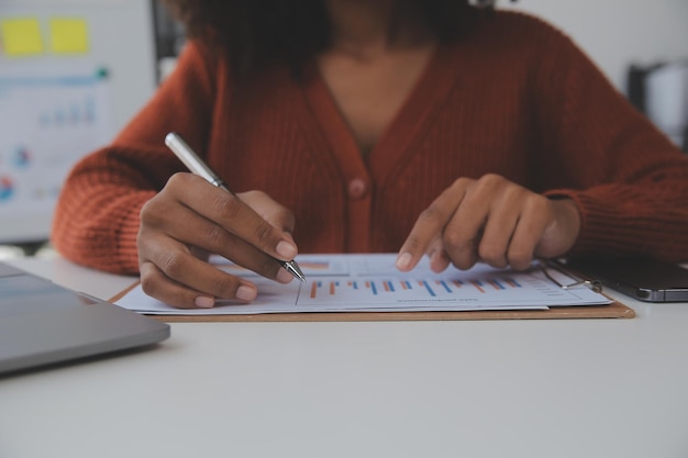 Foto donna d'affari asiatica utilizzando il computer portatile e lavorando in ufficio con il documento della calcolatrice sulla scrivania facendo pianificazione analizzando il concetto di analisi finanziaria di investimento del piano aziendale della relazione finanziaria