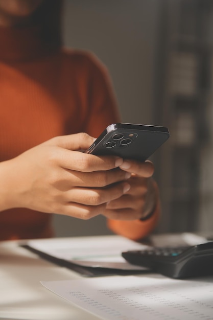 Foto donna d'affari asiatica che utilizza il computer portatile e lavora in ufficio con il documento della calcolatrice sulla scrivania facendo pianificazione analizzando il concetto di analisi finanziaria degli investimenti del piano aziendale della relazione finanziaria