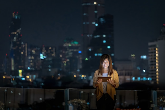 Foto donna d'affari asiatica che utilizza tablet con azione sorriso nell'area del distretto finanziario