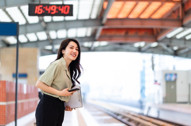 Donna di affari asiatica che aspetta il treno