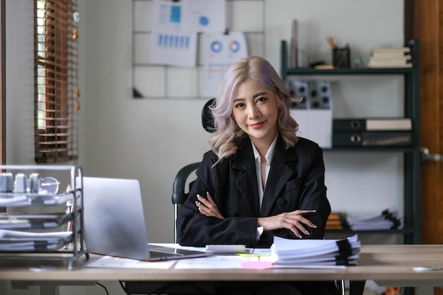 Asian businesswoman with arms looking at camera in the office