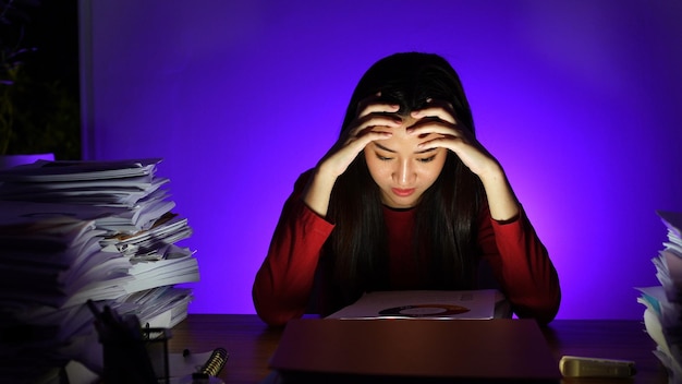 Asian businesswoman working hard late hours with a lot of document at home. Busy and exhausted of work overtime at night.