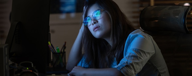 Donna di affari asiatica che lavora duro e che esamina il grafico digitale sul desktop del computer