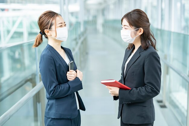 Азиатские деловые женщины в маске и разговаривают в здании бизнеса