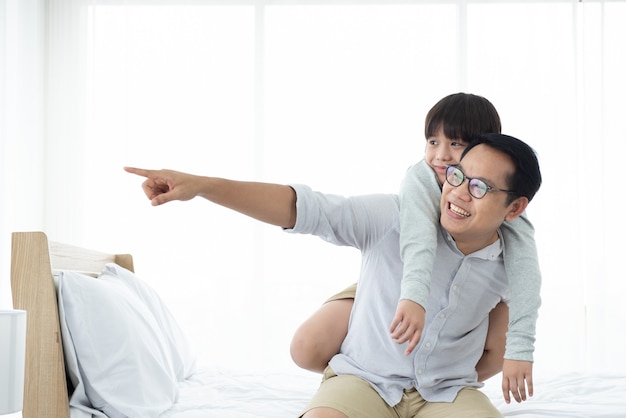 Foto asian riporta il figlio sul letto, famiglia felice a casa.