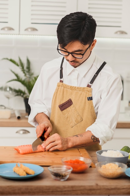 Asian chef cooking ingredients for sushi rolls the cook cuts the salmon fillet with a large knife ad