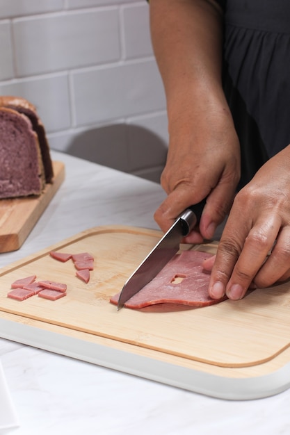 Photo asian chef female hand sliced smoked beef into small pieces. cooking process in the kitchen