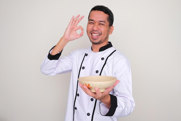 빈 그릇을 보여주면서 웃고 있는 아시아 요리사
