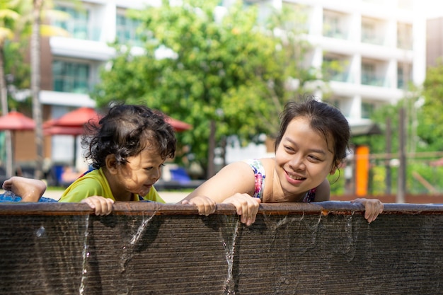 Photo asian child boy learn swimming in a swimming pool with mom. - sunset filter effect