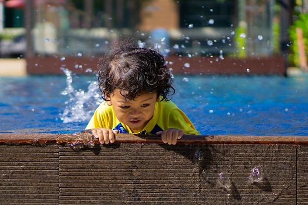 Il ragazzo asiatico del bambino impara nuotare in una piscina