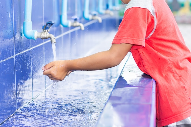 Asian child boy washing his hands before eating food and after play the toys at the washing bowl.