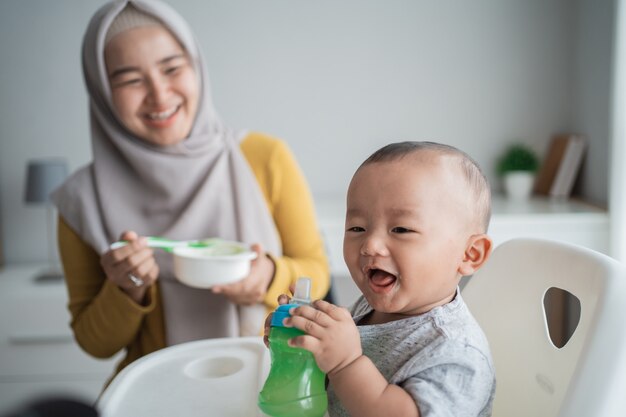 Asian child eating solid food from mother