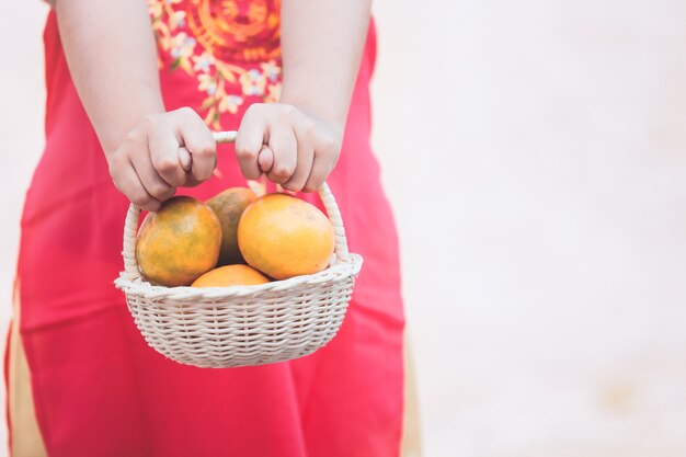 Asian child girl in china traditional dress holding the basket of orange