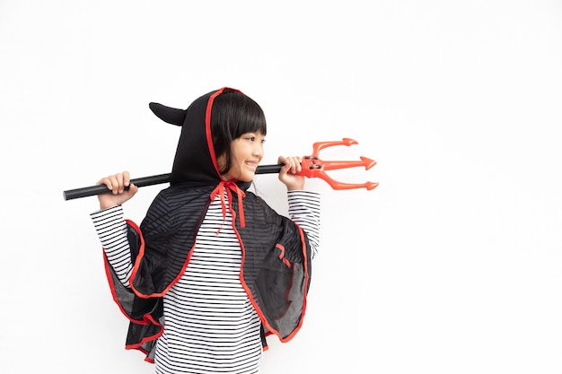 Asian child girl in demon costume holding black and red trident, happy halloween concept