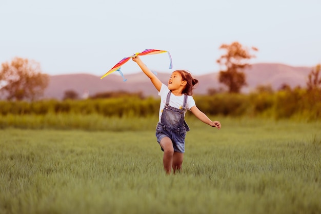 アジアの子供の女の子とカイトが走っている父