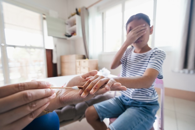 Asian child girl feeling scared while parent helping her perform first aid finger injury after she has been an accident.