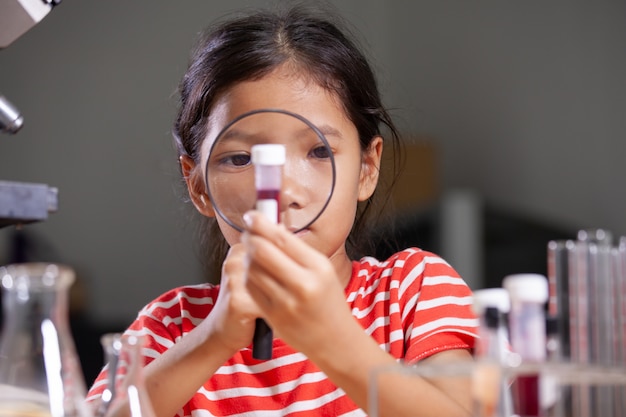 Азиатская девушка ребенка делая химический эксперимент в лаборатории.
