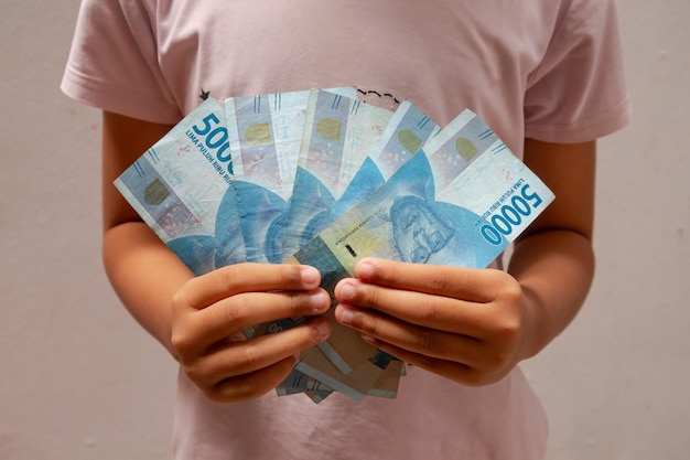 Photo asian child holding indonesian money fifty thousand rupiah indonesian rupiah banknotes