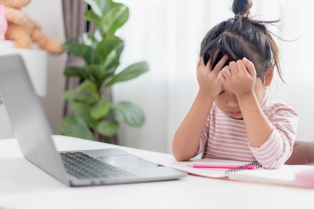 Asian child is serious about studying homework during online\
lesson at home social distancing during quarantine selfisolation\
online education concept homeschooling study online video call\
teacher