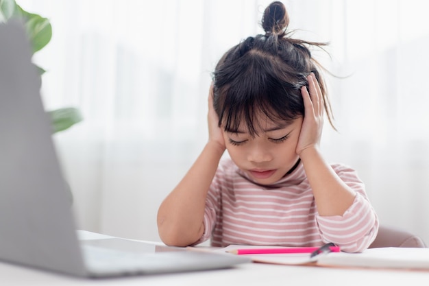 Asian child is serious about studying homework during online lesson at home social distancing during quarantine selfisolation online education concept homeschooling study online video call teacher