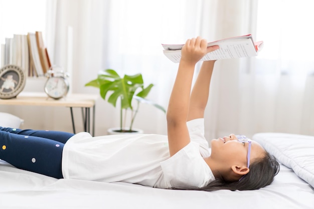 Asian child little girl reading books lying on the bed at home