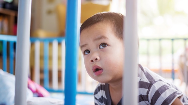 Bambino asiatico che si trova in una barriera di sicurezza.