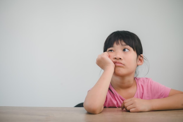 Asian child rest her cheeks on the fists with moody face