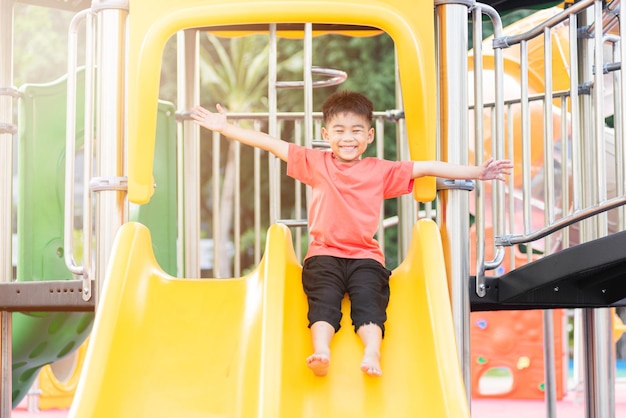 Asian child smiling playing on slider bar toy outdoor playground