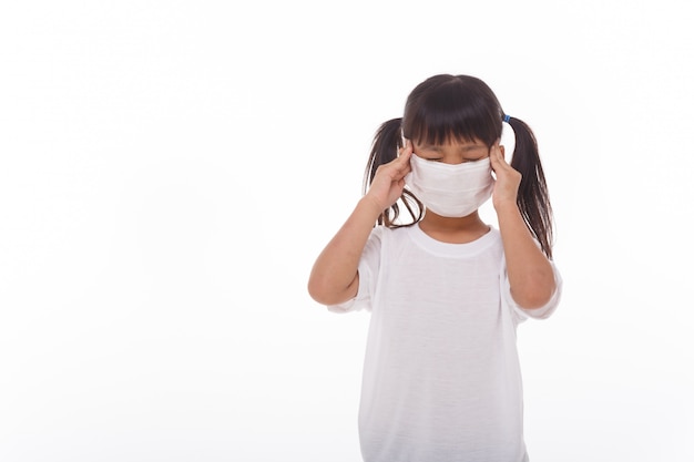 Азиатский ребенок в медицинской маске чувствует головную боль на белом