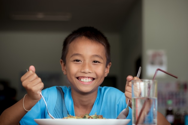 食堂やカフェテリアで健康的な食べ物を食べるアジアの子供の少年。