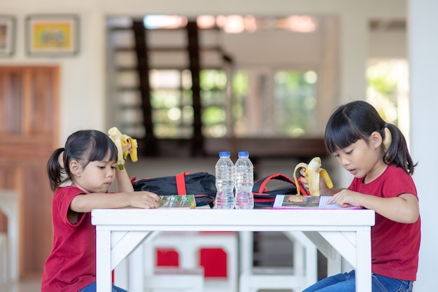 昼食や朝食を食べている食堂のアジアの子供たちは楽しんでいます