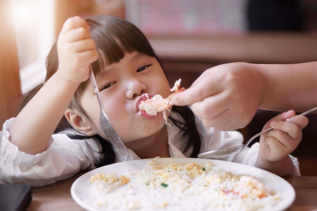 かわいい、子供の女の子、エビやエビの揚げ米を食べるアジアの子供たち