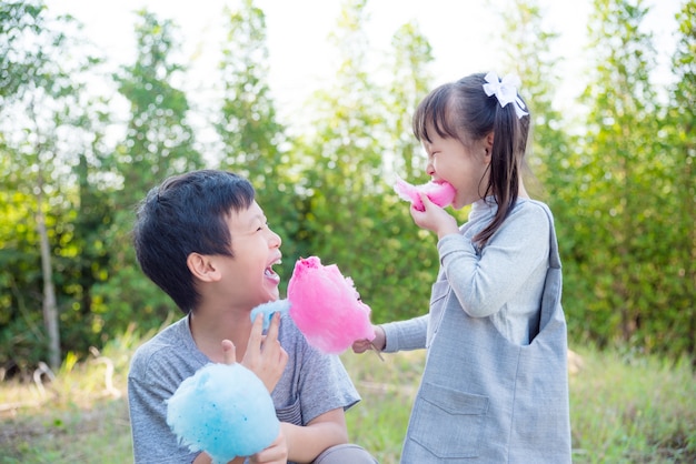 Asian children eating cotton candy in park together