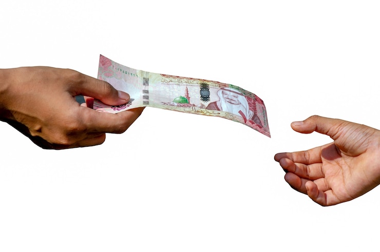 Photo asian children's hand with 100 riyal, the currency of saudi arabia, concept of giving. shallow focus and isolated on white background