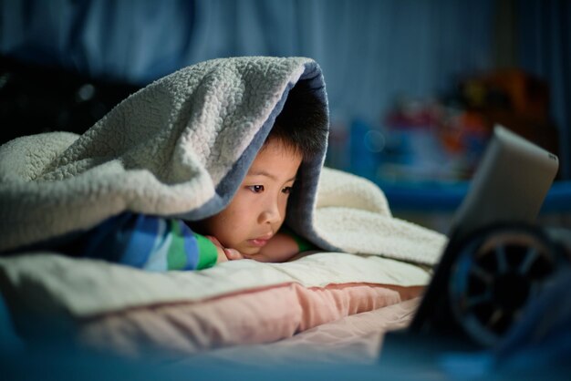 스마트폰을 하는 아시아 중국 소년 아이는 전화를 사용하고 게임에 중독된 게임과 만화를 사용합니다.