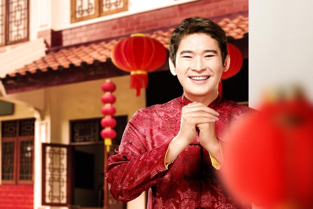 An Asian Chinese man in a cheongsam dress with a congratulations gesture. Happy Chinese New Year