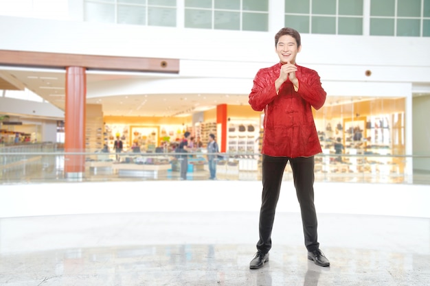 Un uomo cinese asiatico in un abito cheongsam con gesto di congratulazioni