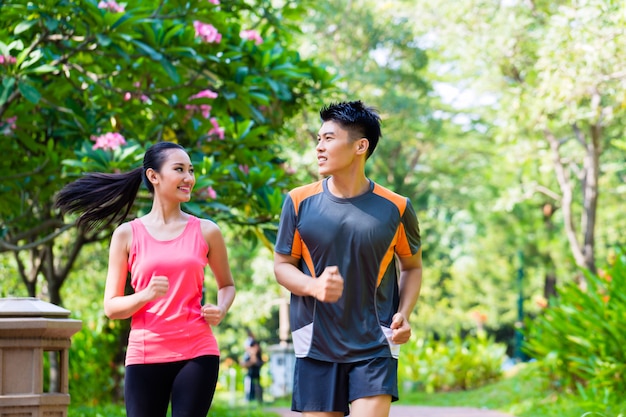 Asian Chinese man and woman jogging in city park