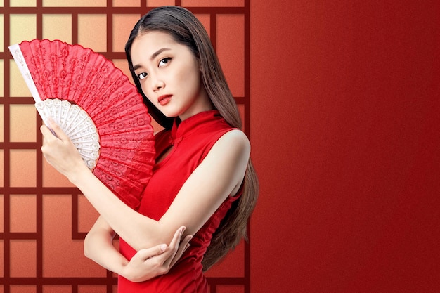 Asian Chinese woman in a cheongsam dress holding fan celebrates Chinese New Year. Happy Chinese New Year