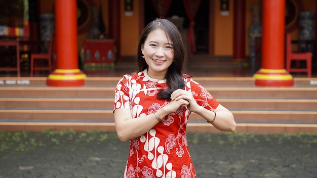 Asian Chinese woman in a cheongsam dress with congratulations gest at vihara