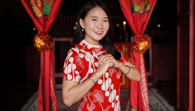 Asian Chinese woman in a cheongsam dress with congratulations gest at vihara