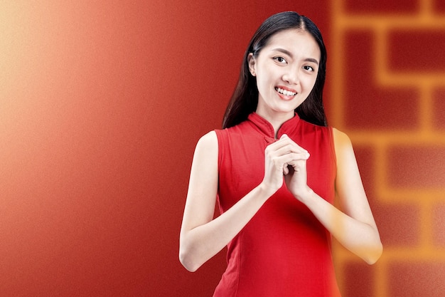 Asian Chinese woman in a cheongsam dress with congratulations gesture. Happy Chinese New Year