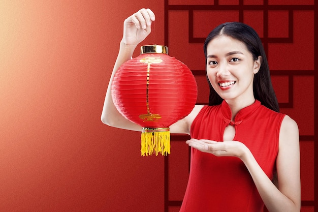 中国のランタンを保持しているチャイナドレスのアジアの中国人女性。旧正月おめでとう