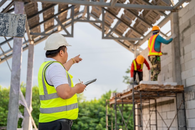 Asian Civil Engineers are working with construction workers who are laying bricks at the construction site