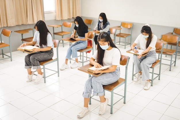 Asian college students back to school with facemask and keep\
social distance while study in the classroom to prevent covid-19\
pandemic