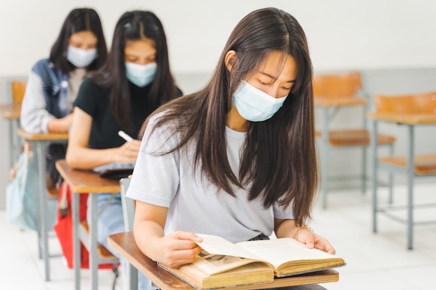 Asian college students back to school with facemask and keep\
social distance while study in the classroom to prevent covid-19\
pandemic