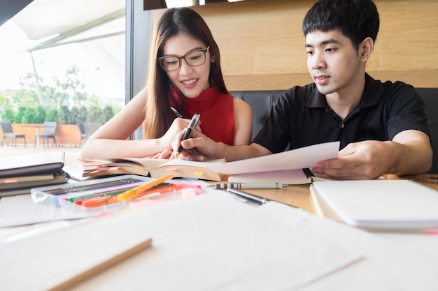 Asian college students talking while doing homework in the library