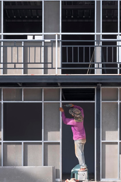 Asian construction worker installing precast concrete wall inside of house construction site