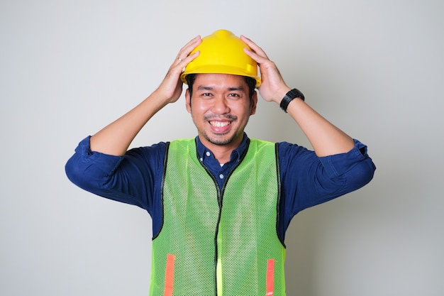 Asian construction worker smiling confident while holding his yellow hard hat