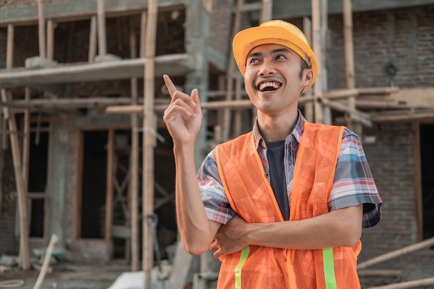 Asian contractor stands wearing a safety helmet and vest